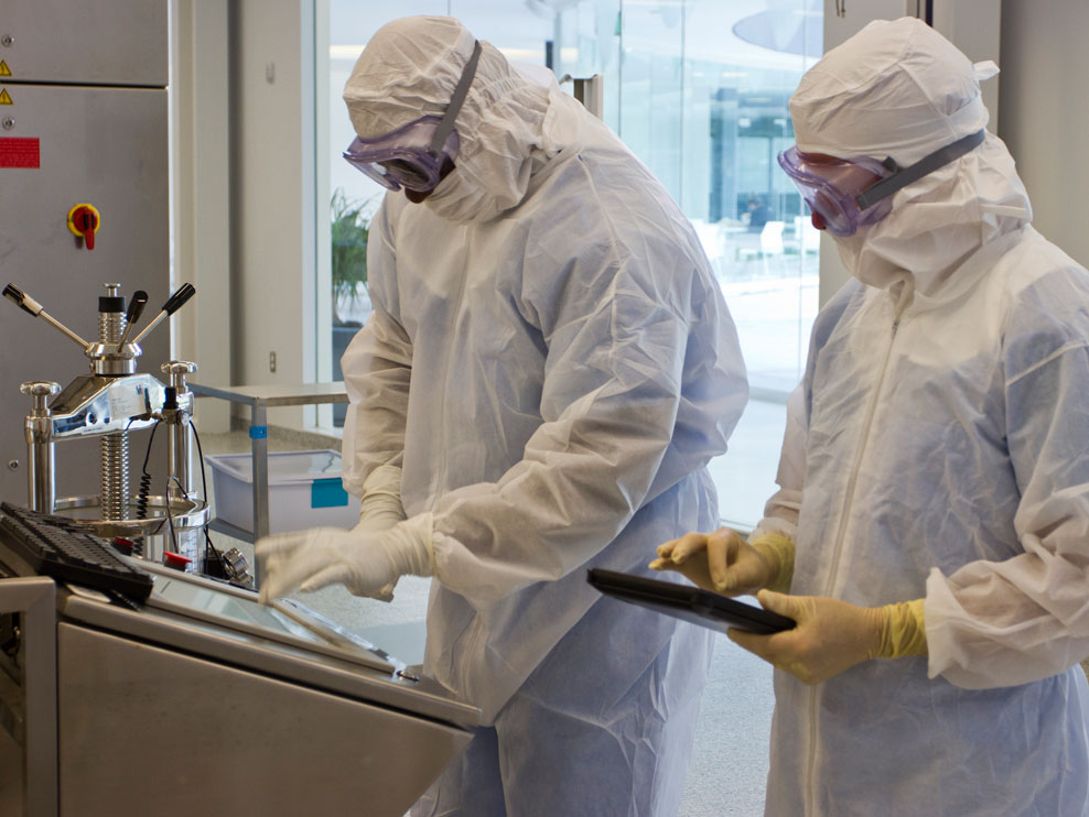 Two people in white protective gear looks work at a health organization