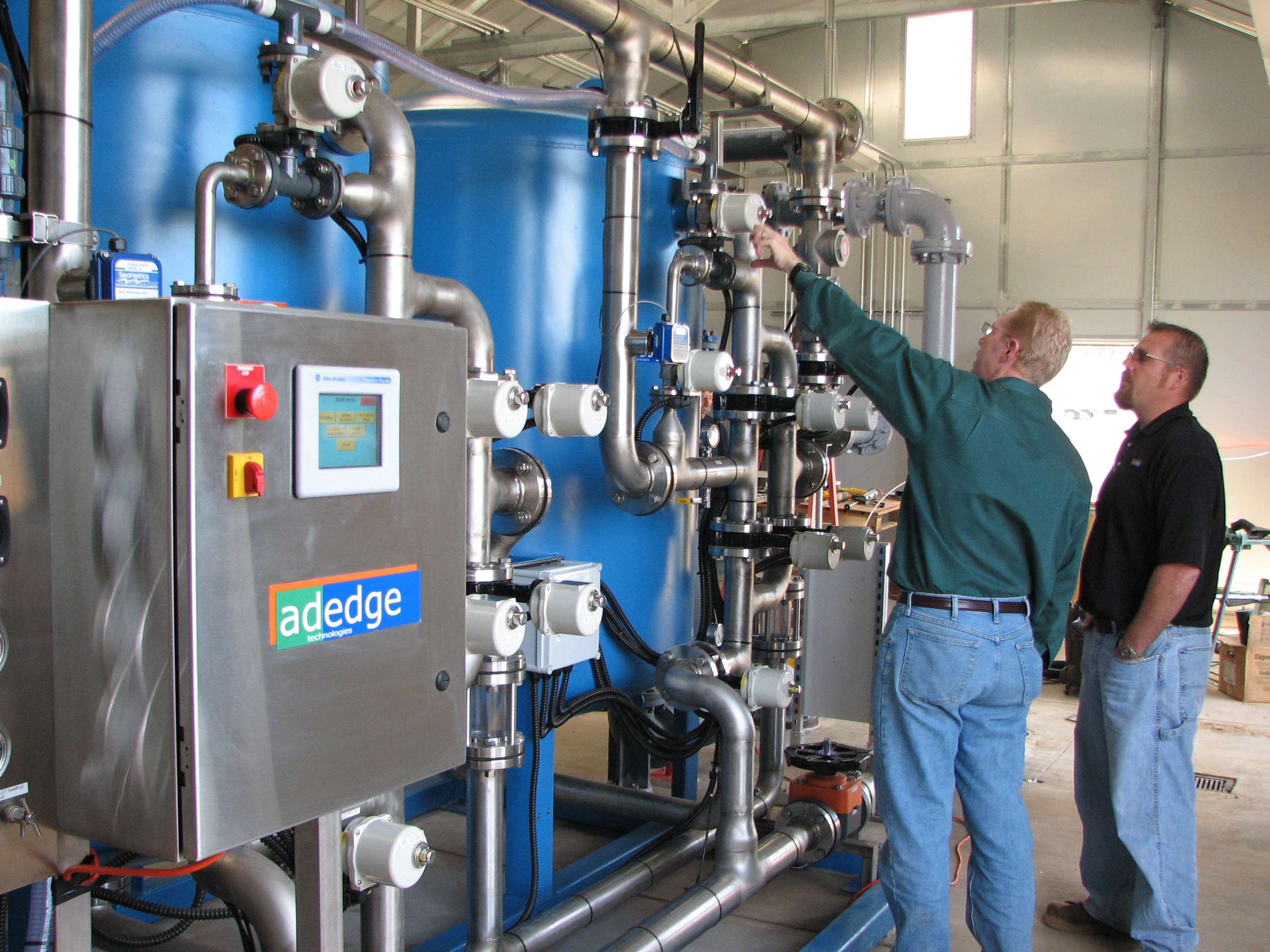 two people work on large barrel machines