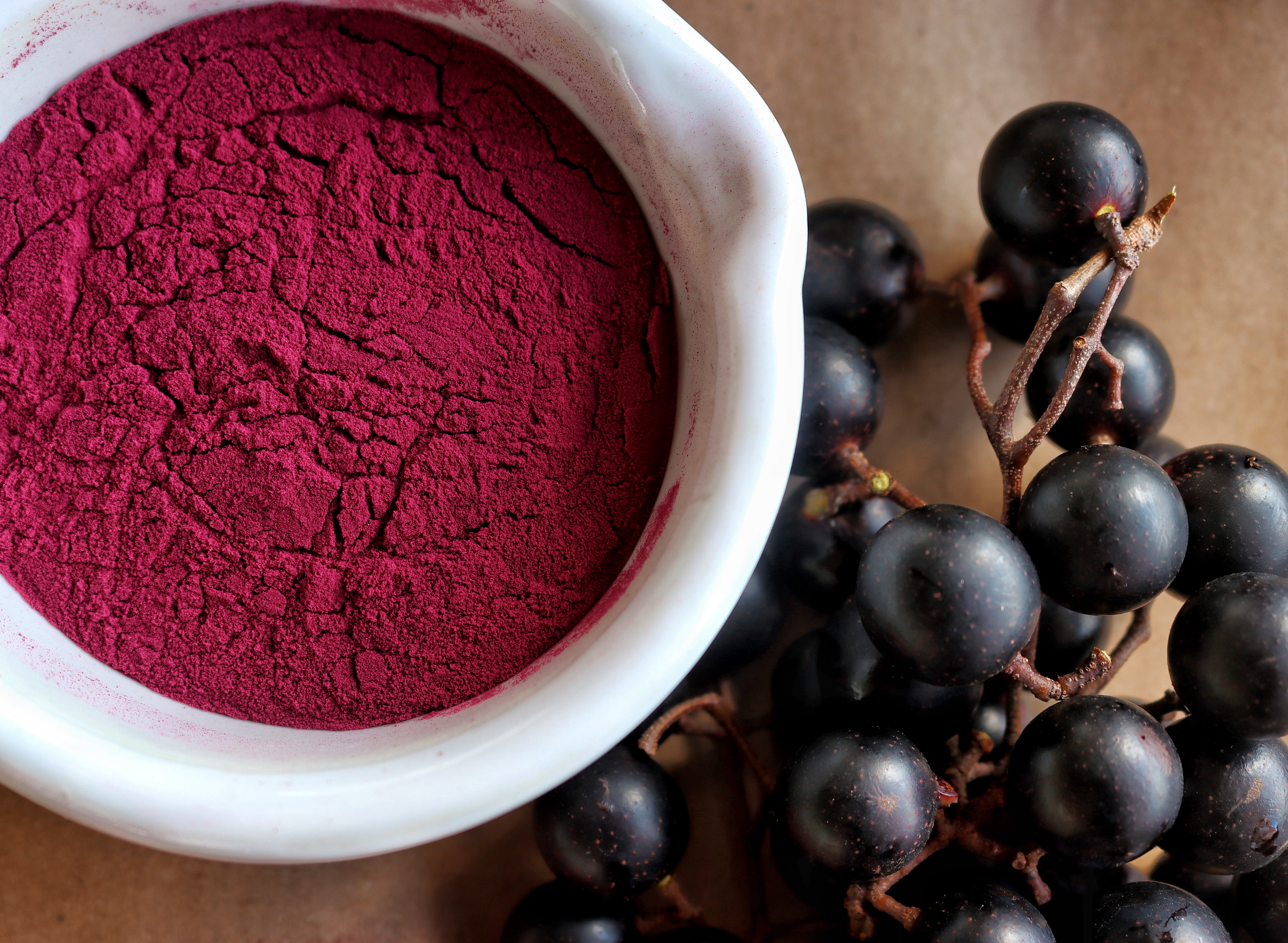 a bowl of Muscadine powder with grapes next to it