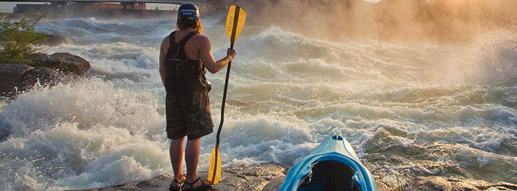 kayaker standing in front of river rapid