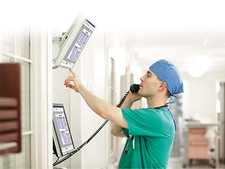 nurse on the phone checks a monitor on the wall