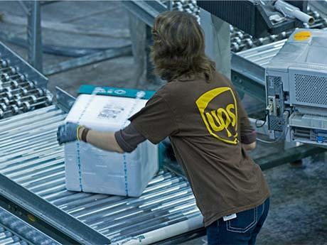 UPS employee puts box on conveyer belt