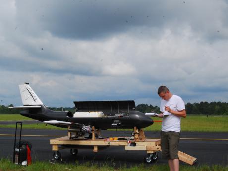 Aerospace Research & Education A person in casual clothes stands on an air field in Georgia next to a plane and takes notes.