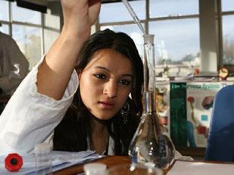 Workforce and Education Woman with an eye dropper standing over a glass test tube