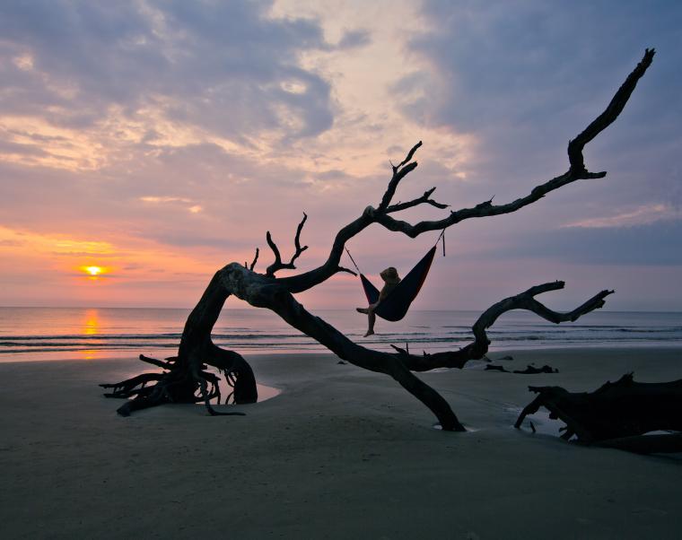 kid sitting in hammock by georgia beach watching sunset 