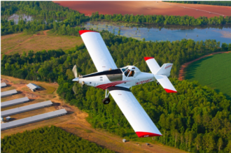 Small airplane flying over farm fields