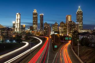 Timelapse view of a city skyline at night with cars rushing by.